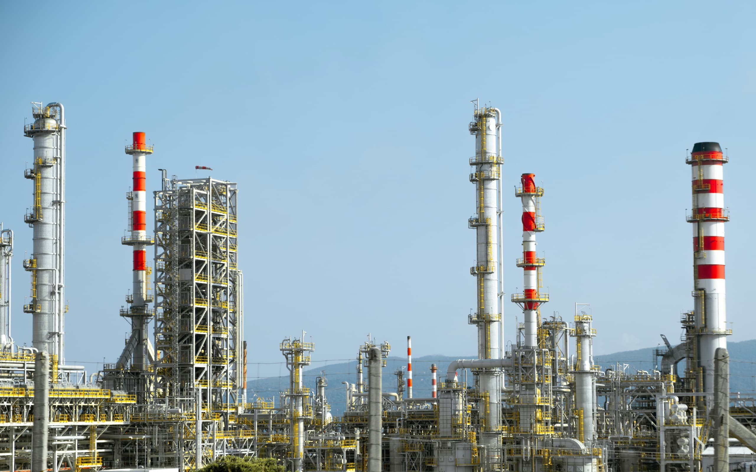 Oil refinery towers under a clear sky